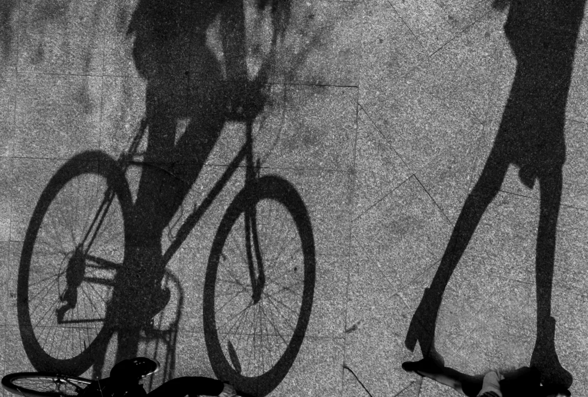 Two bicycle shadows stretched across sunlit pavement